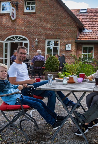 Eine Familie sitzt am Tisch im Innenhof der Gastronomie.